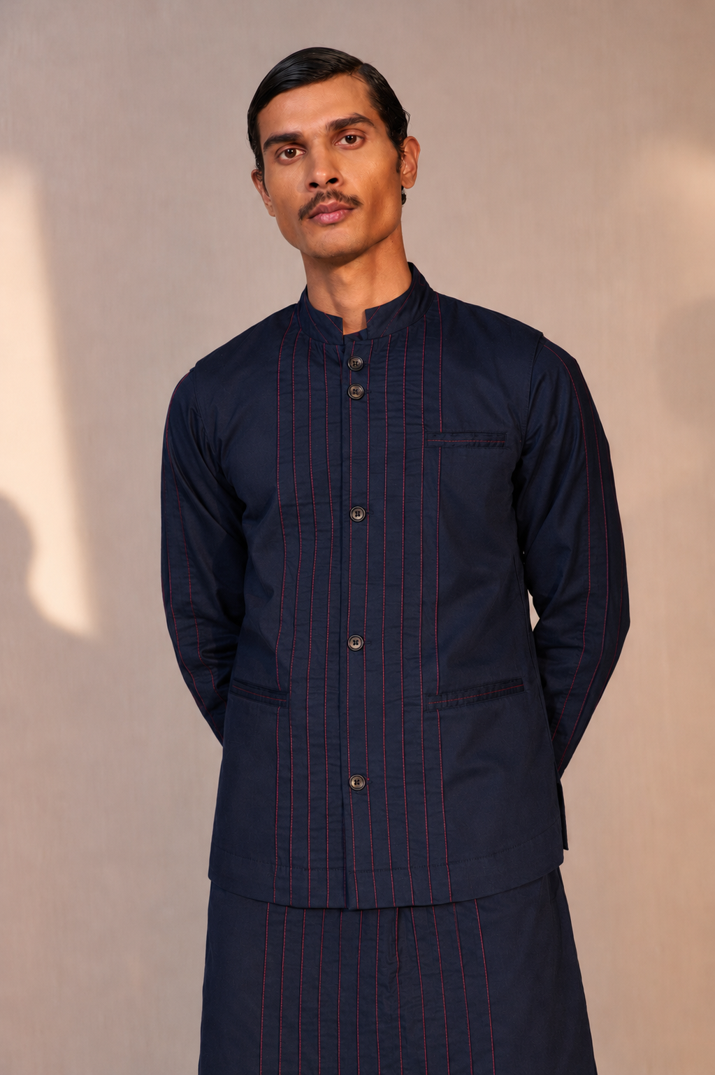 Man wearing a dark blue traditional outfit with a plain background